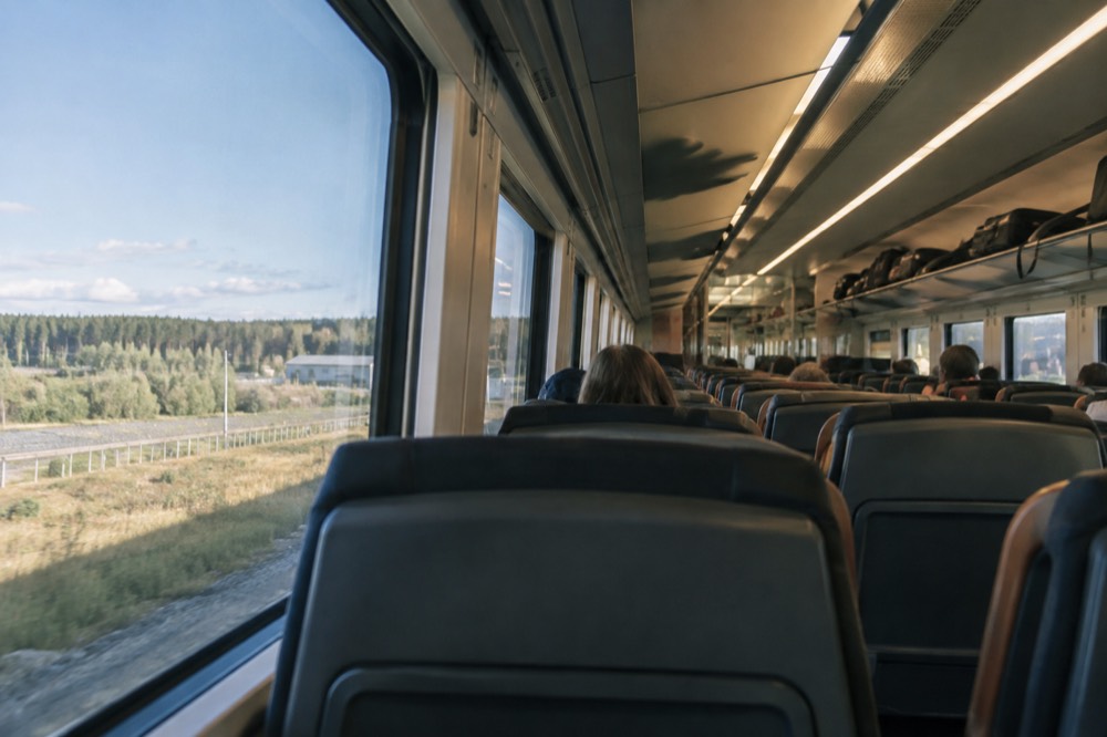 Interior of a modern Norwegian train with passengers seated and luggage racks visible
