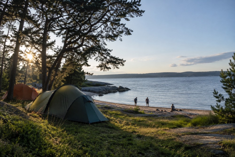 Tents on grass near a sandy beach on a small fjord island