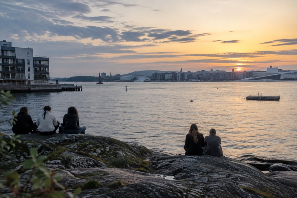 Evening light over a fjord beach with people sitting on rocks