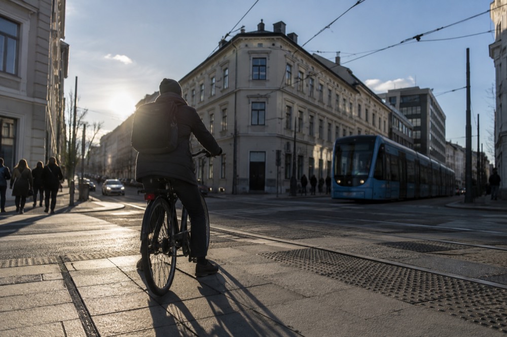 A cyclist waiting at a crossing beside tram tracks on a city street