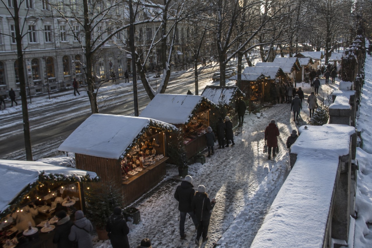 Wooden market stalls decorated with lights along a snowy city street in Oslo