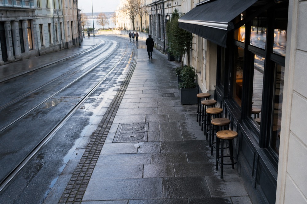 Empty bar stools in front of a closed storefront on a quiet evening street