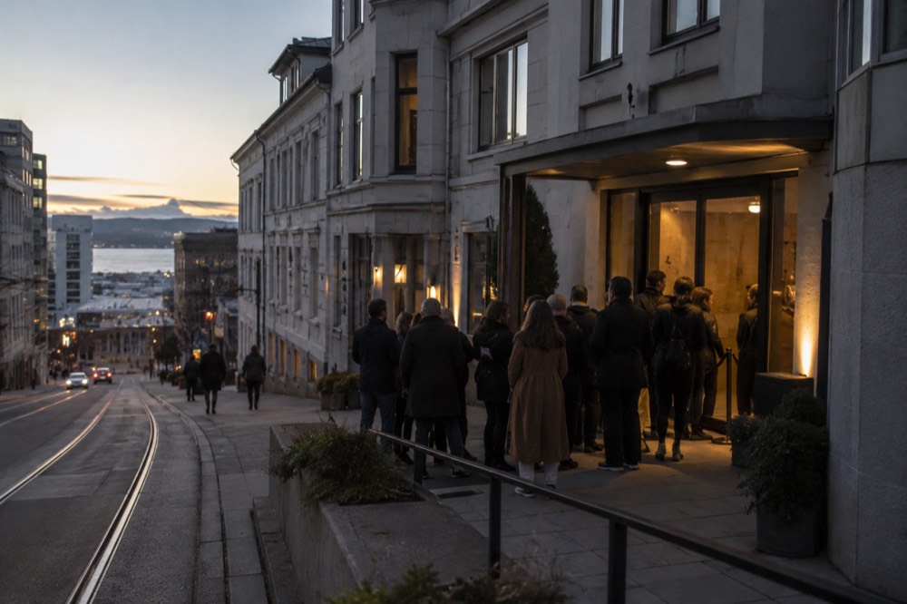 People in jackets waiting outside a lit venue entrance at night
