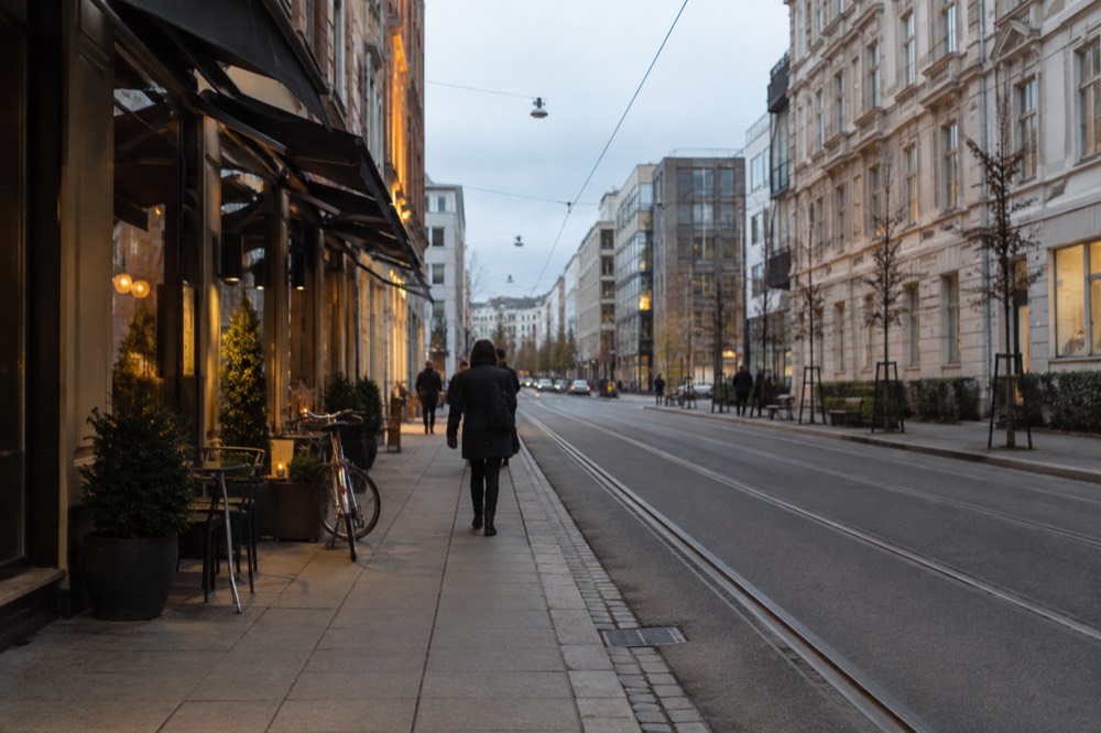 A quiet Oslo street with a bicycle and shop awnings in soft evening light