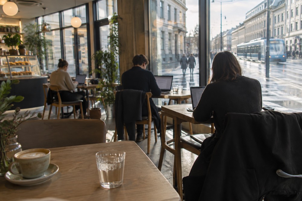 People with laptops and coffee inside a bright Oslo cafe