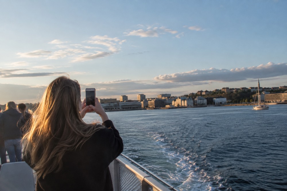 Visitor photographing the Oslofjord from a boat deck with a phone