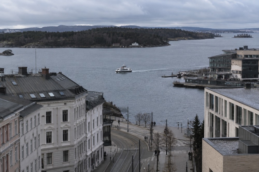 A small electric boat cruising past forested shoreline on the Oslofjord