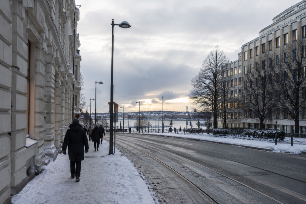 People walking along a snowy Oslo street in low winter light