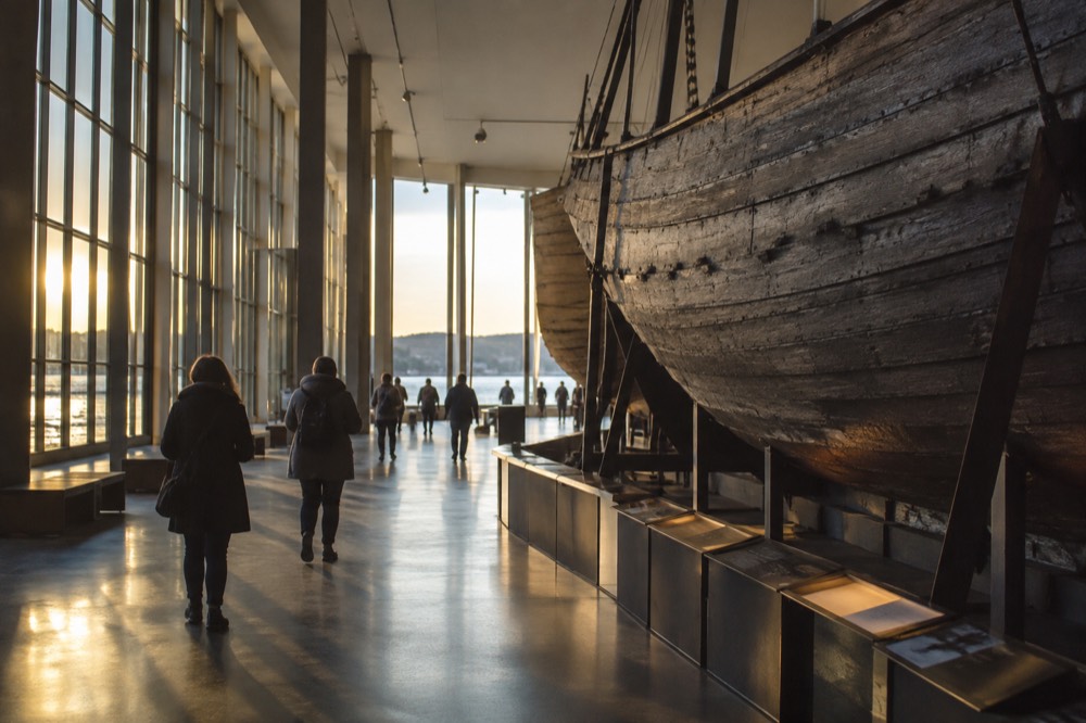 Visitors walking through a museum hall with a large ship hull on display