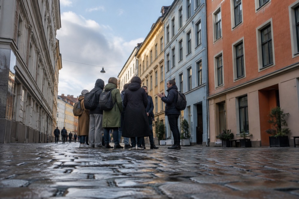 A tour guide speaking to a small group on a pedestrian street lined with colorful historic buildings