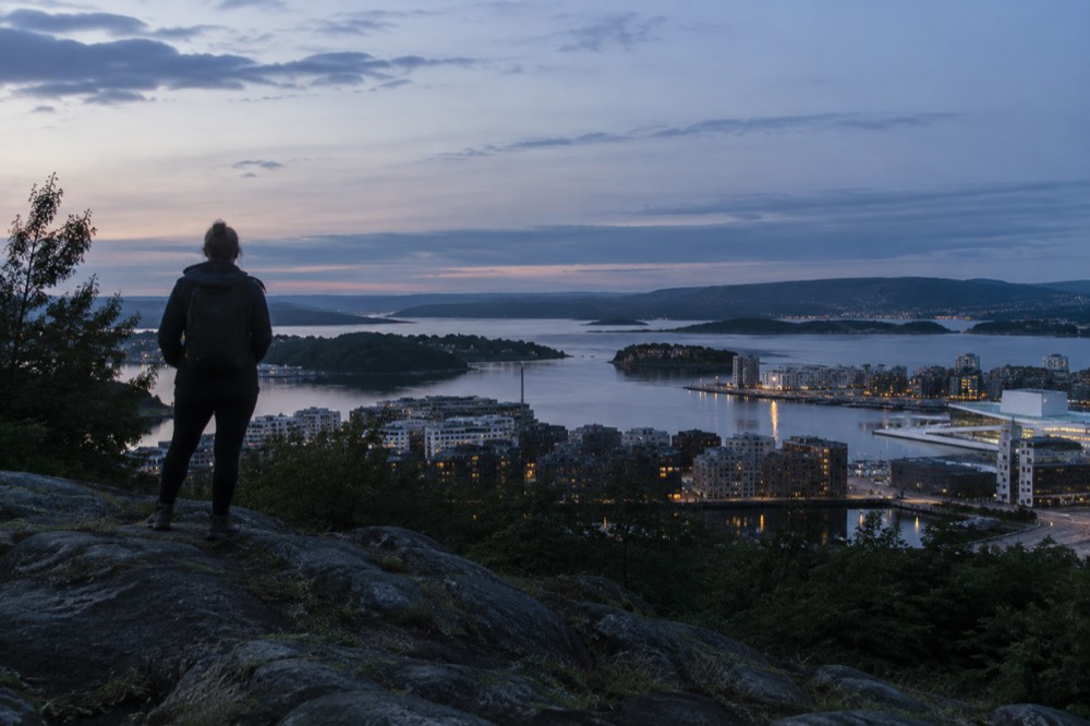 Hiker on a rocky viewpoint above the Oslofjord in evening light