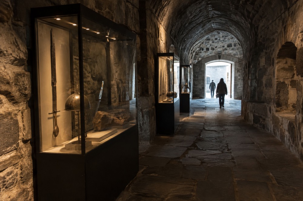 Stone corridor of a fortress museum with display cases lit softly