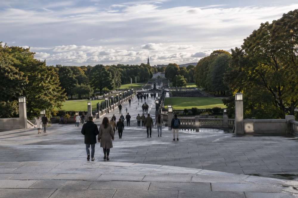 Visitors strolling the granite avenues and steps of Vigeland Park under an open sky