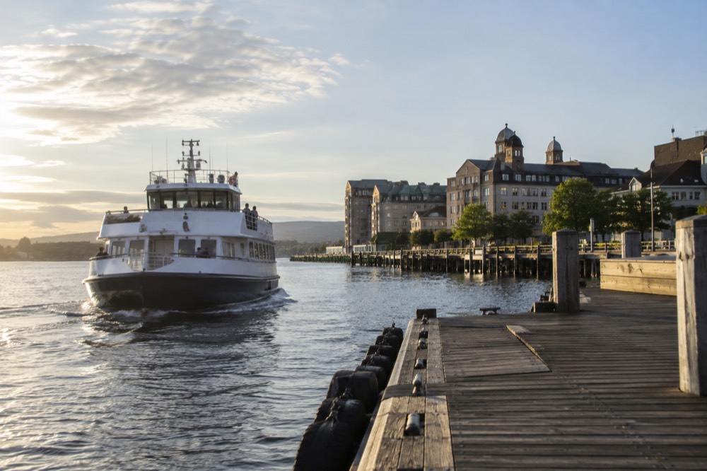 Passenger ferry approaching a wooden pier with museum buildings beyond
