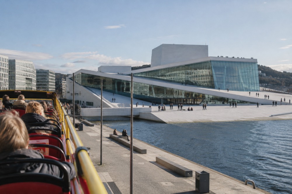 Open-top sightseeing bus driving past the Oslo Opera House on a bright day