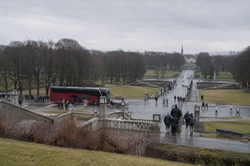 Sightseeing bus stopped near the Vigeland sculpture park with tree-lined paths