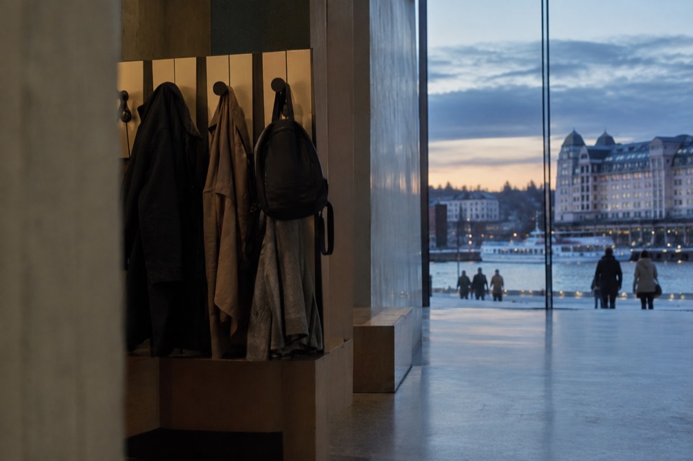 Coats and small backpacks hanging on numbered pegs in a museum cloakroom