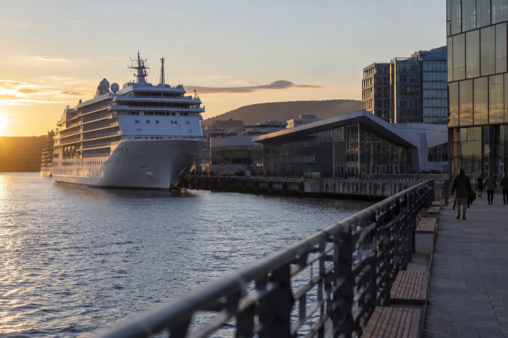 White cruise ship docked at a modern Oslo waterfront terminal near glass buildings