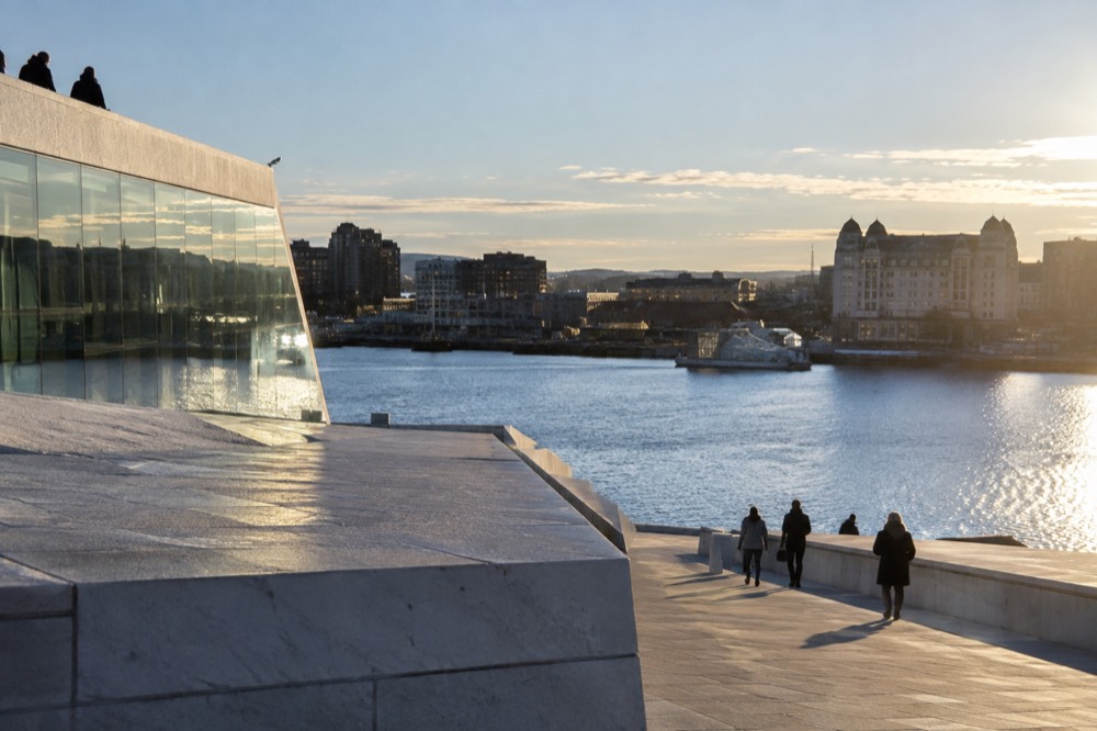 Oslo city center seen from the harbor with the Opera House roof and fjord in the distance