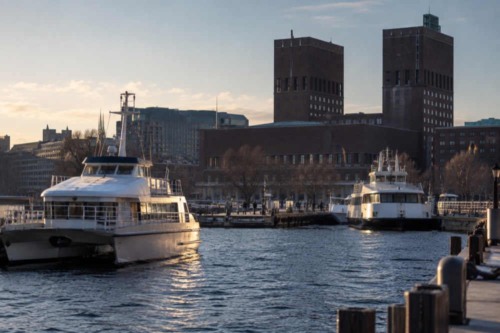 Ferry boats moored at the Aker Brygge waterfront with the City Hall tower behind