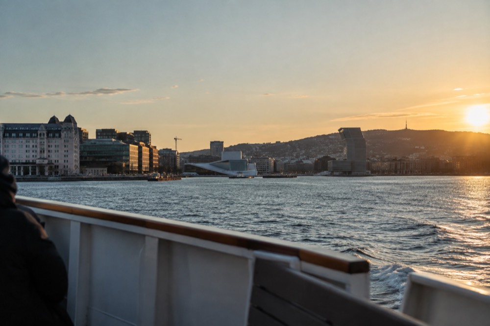 A silent electric boat cruising on the Oslofjord with the city skyline and forested hills behind