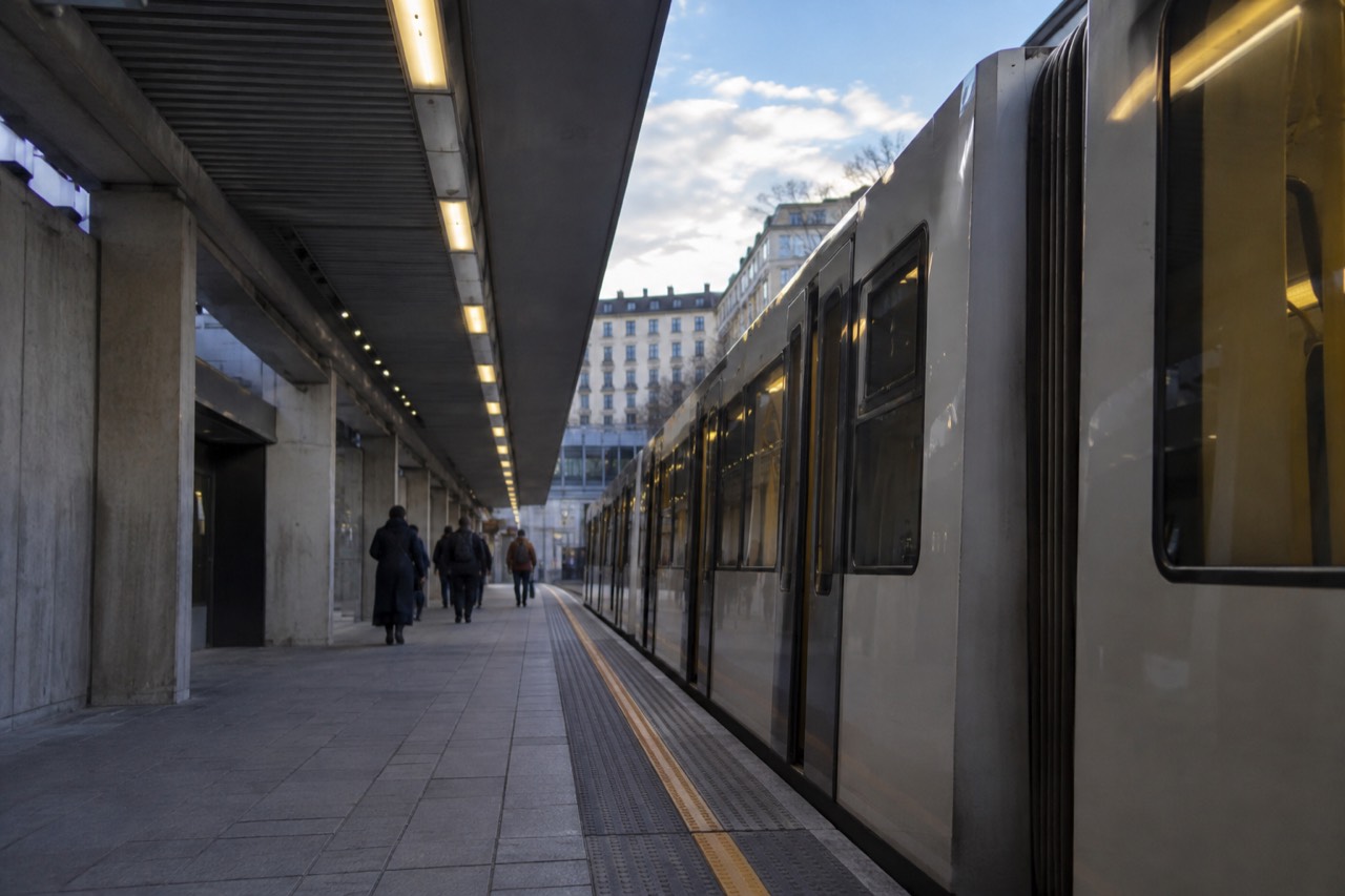 A metro platform in Oslo with a train waiting at an illuminated station
