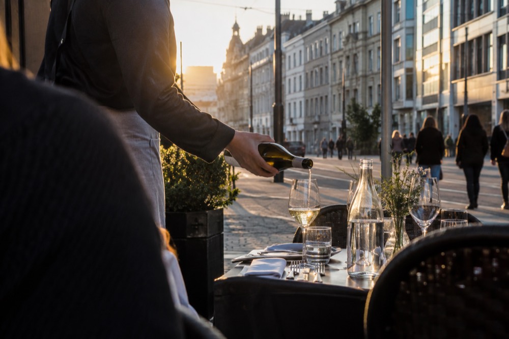 Sommelier pouring white wine into a glass at a set table