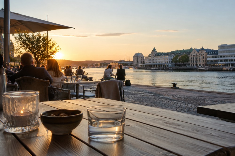 People on a waterside terrace in bright late evening light
