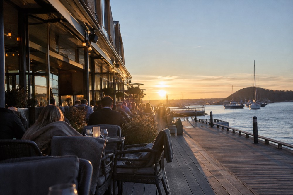People sitting outside a waterfront bar in Aker Brygge during late evening light