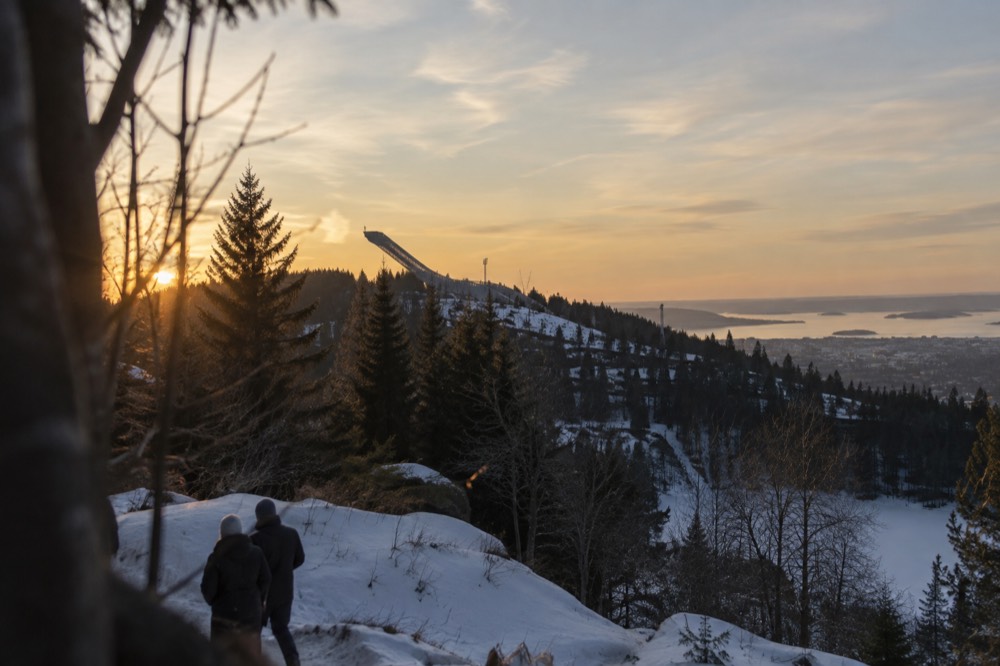 Ski jump tower on a forested hill above Oslo at dusk