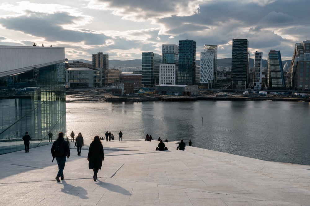 White marble slopes of the Oslo Opera House roof with the Barcode skyline behind