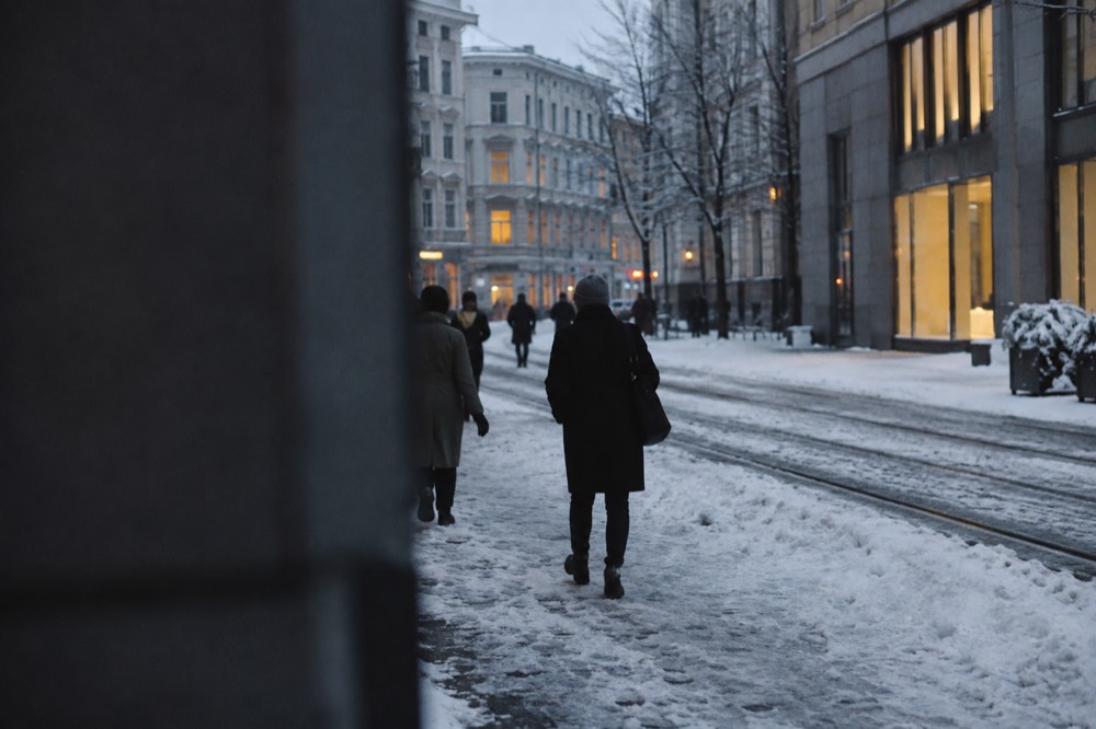 Snow-covered Oslo street with warm window light in the blue afternoon