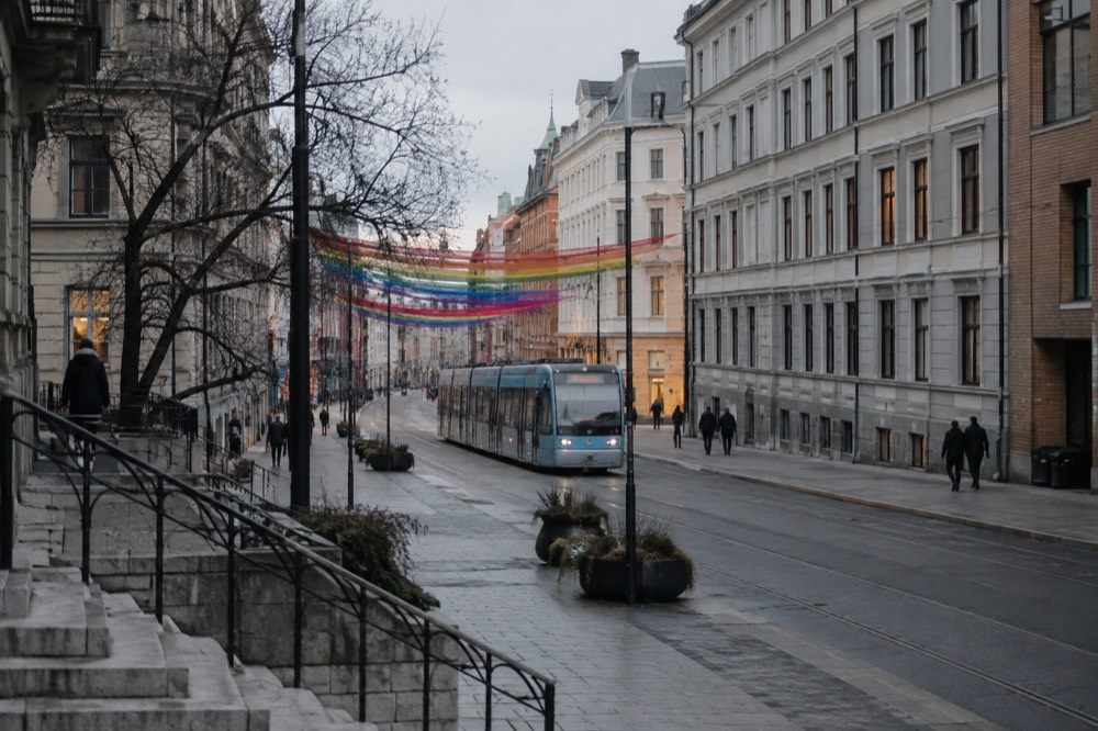 A tram moving along a street with rainbow decorations in the background