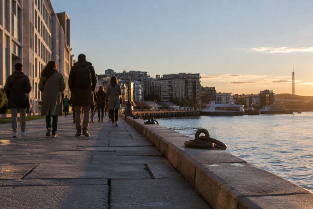 People walking along a waterfront promenade in warm evening light