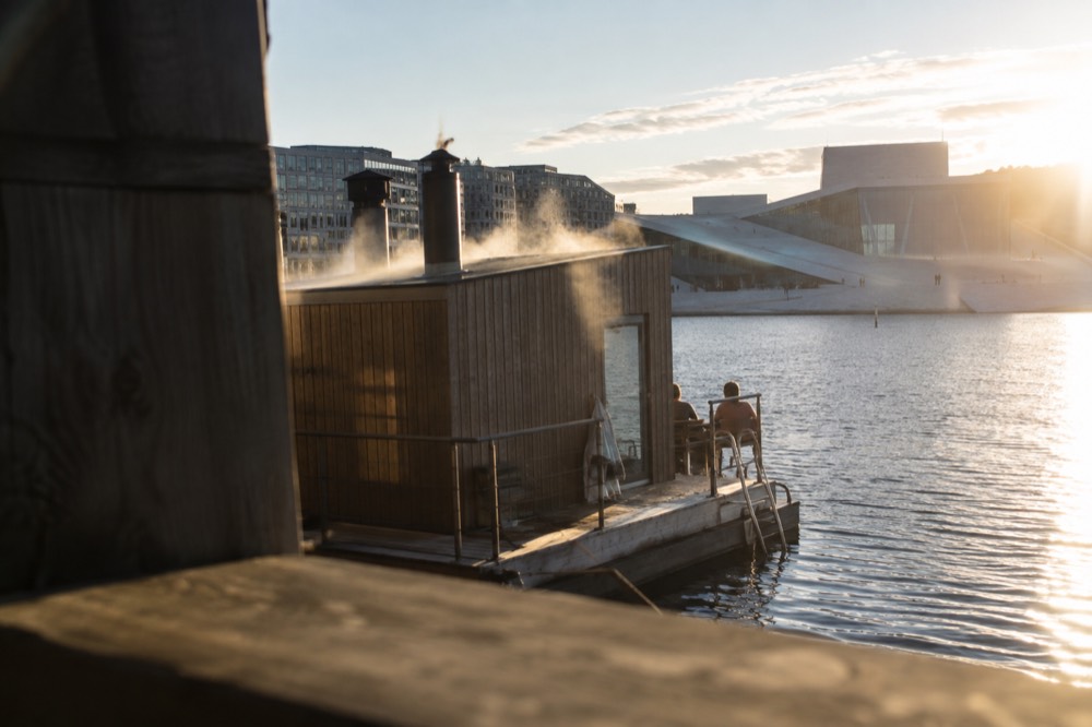 Steaming sauna raft moored in the Oslo harbor with the Opera House in the background