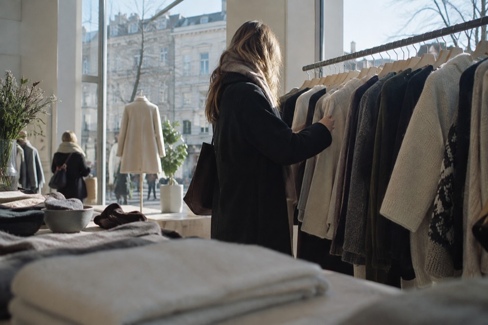 Customer browsing a rack of clothing in a bright Oslo boutique