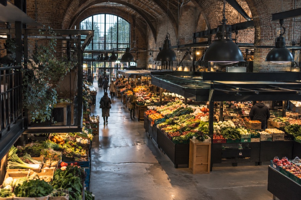 Interior of a food hall with stalls under industrial brick vaulting