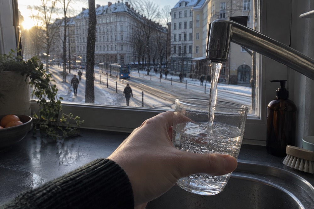 A glass of water filled from a modern kitchen tap beside a window with soft northern light