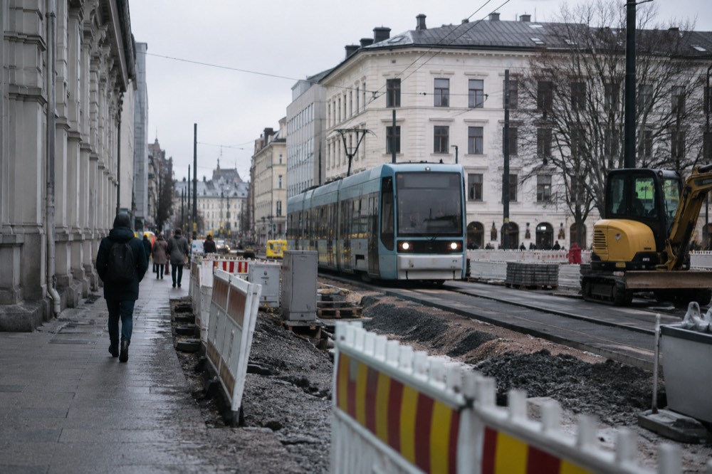 A tram passing construction barriers and roadworks on an Oslo street