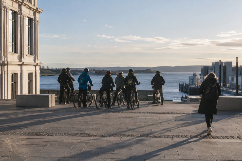 A bicycle tour group paused at a waterfront viewpoint with the Oslofjord behind them