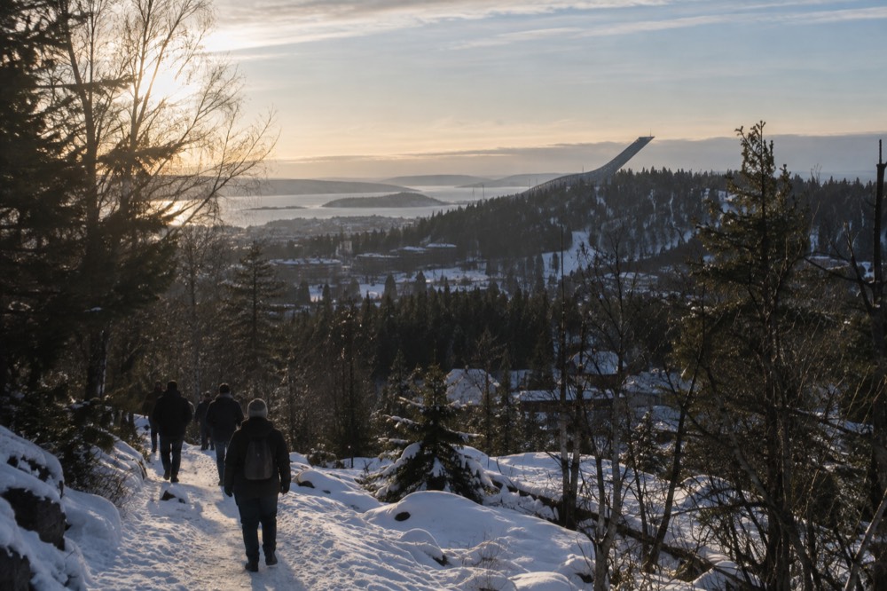 Ski jump tower on a forested hill above the city and fjord