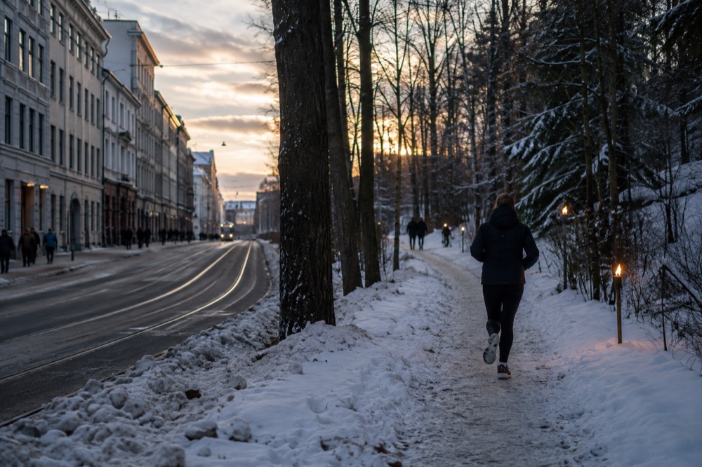 Snow covered forest trail with torches at dusk near Oslo