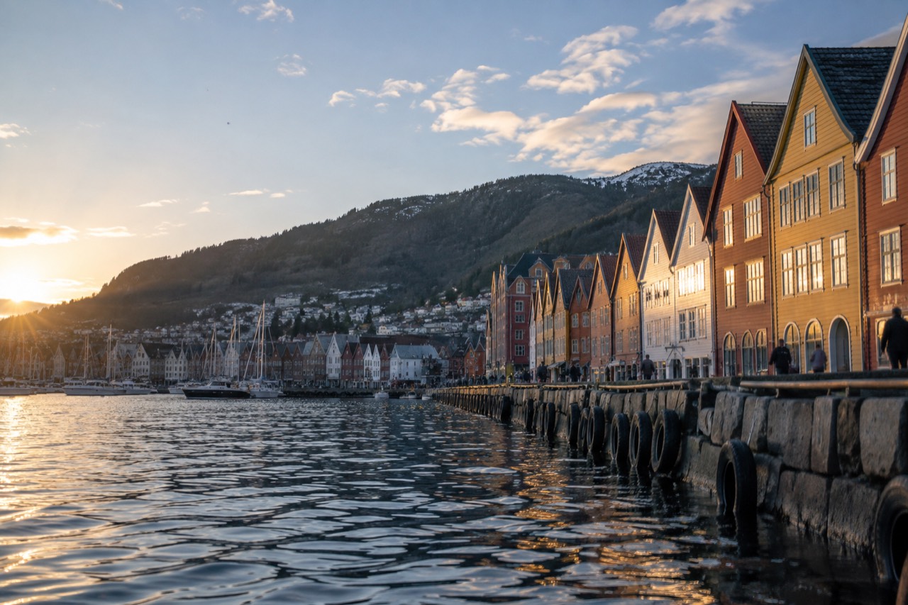 Colorful waterfront buildings in Bergen with a fjord and hills behind them