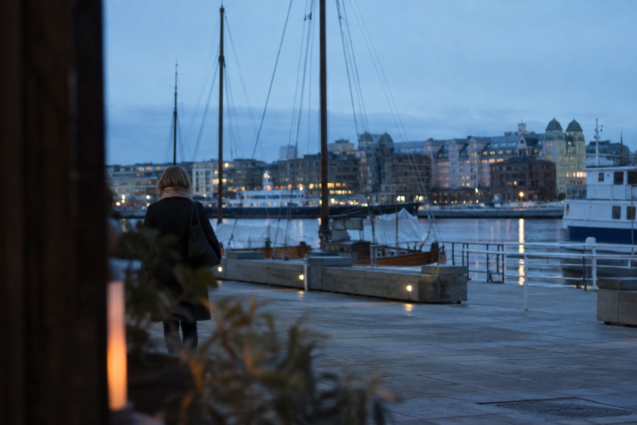 Harbor front with moored boats and city buildings across calm water