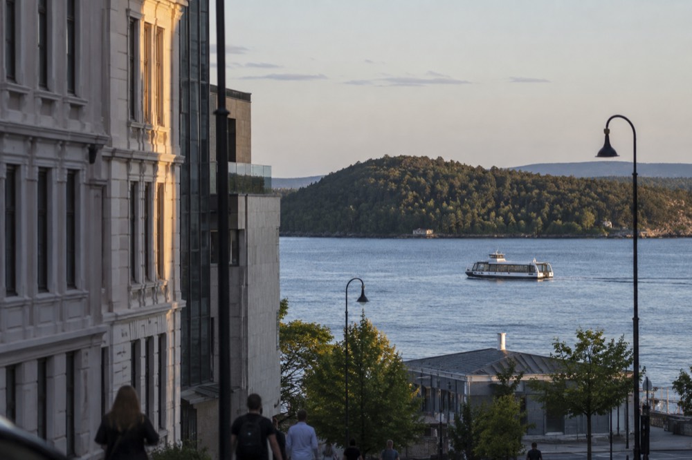 Silent electric boat cruising on the Oslofjord past forested shoreline