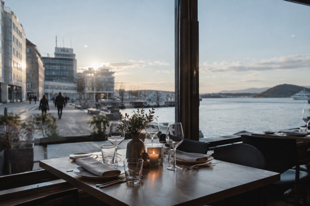 A restaurant table set for dinner beside a fjord-facing window in Oslo