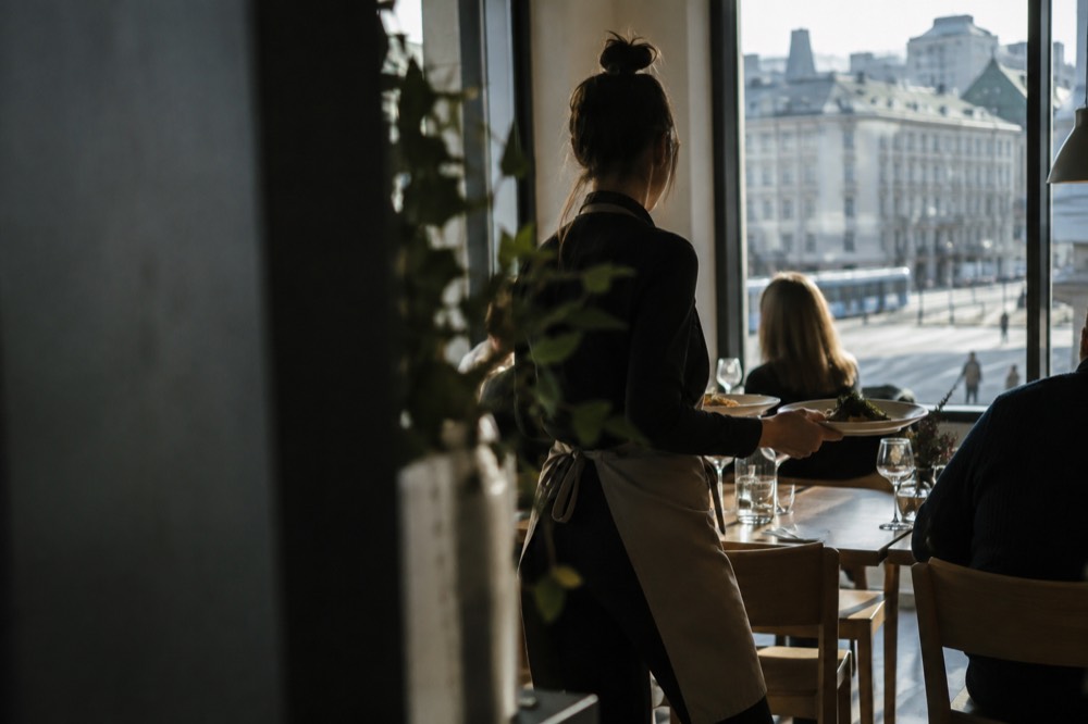 A server bringing plates to a dinner table in an Oslo restaurant