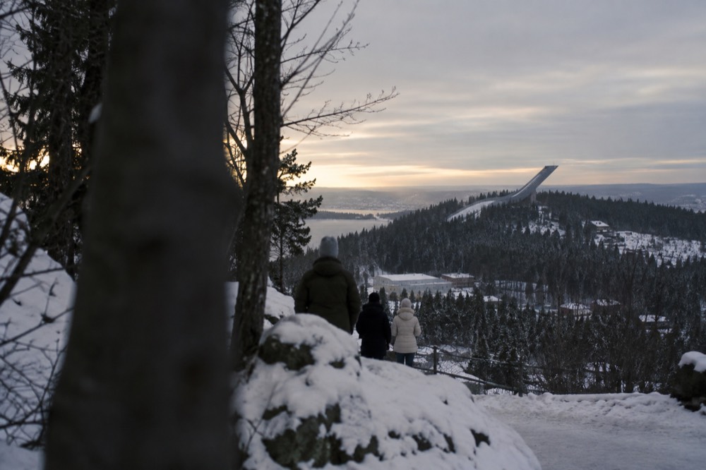 Snow-covered ski jump tower above dark forest at dusk