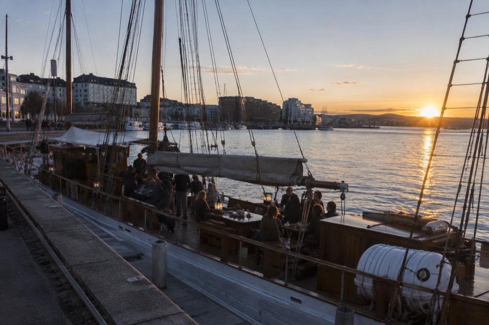 Wooden sailing ship on the Oslofjord at sunset with diners on deck