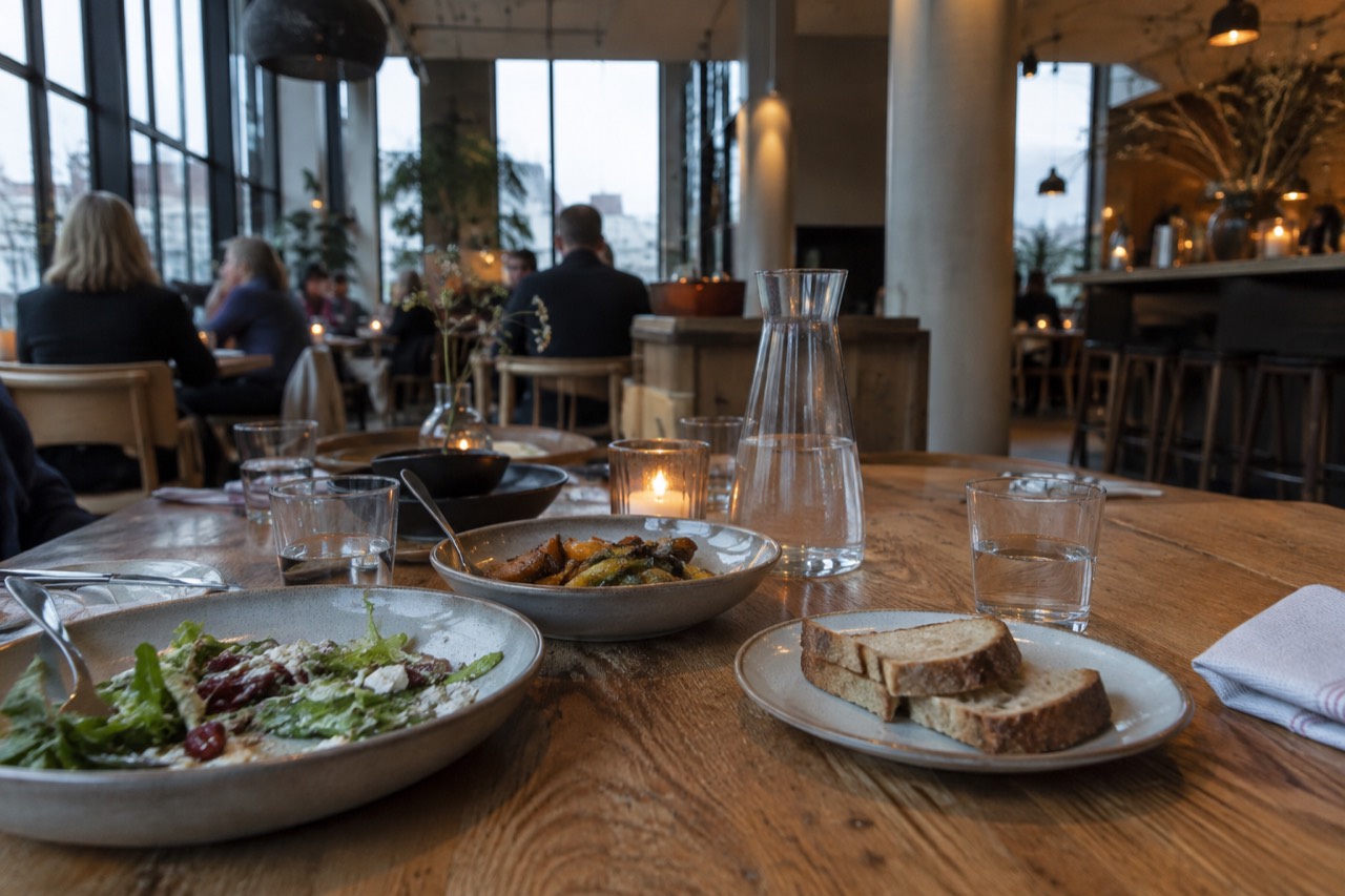 Long wooden table with shared dishes in a bright Oslo restaurant
